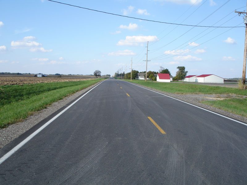 A road with no traffic on it and grass in the background.