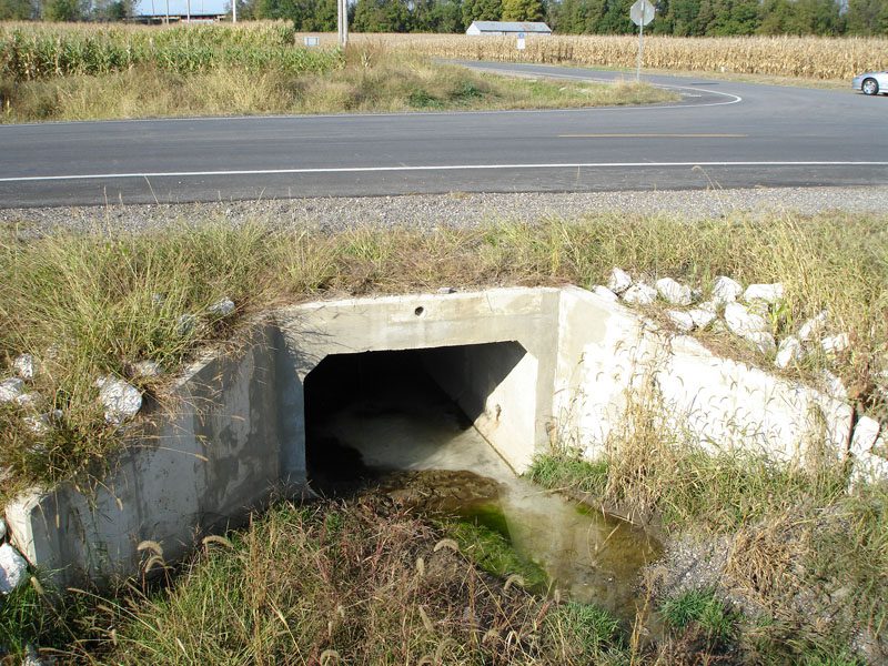 A large concrete tunnel is in the middle of nowhere.