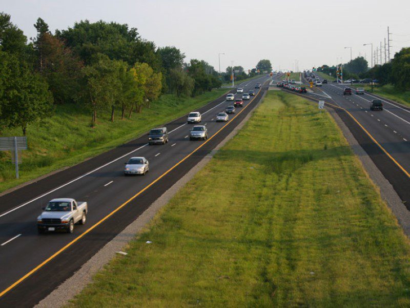 A highway with many cars on it and grass