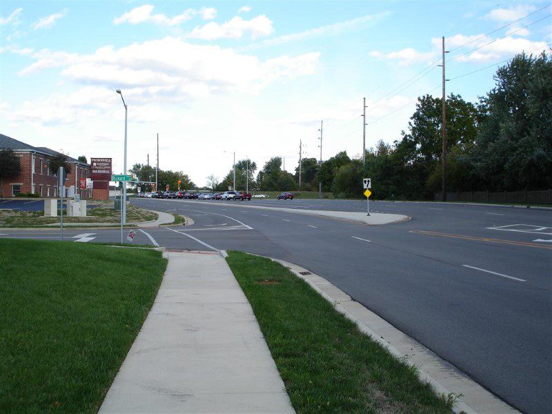 A street with grass and trees on the side.
