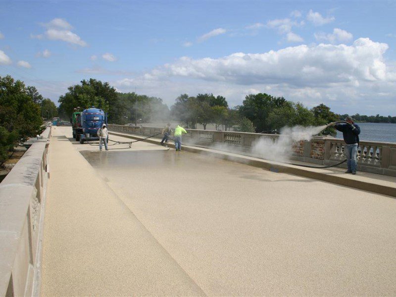 A person spraying water on the side of a road.