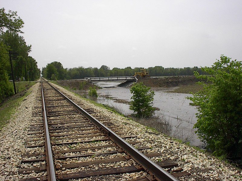 A train track with trees and water in the background