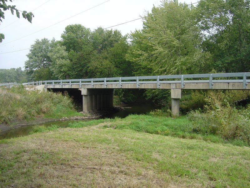 A bridge over a river with trees in the background.