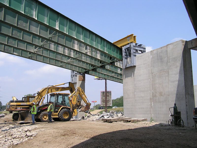 A construction site with a large green bridge.