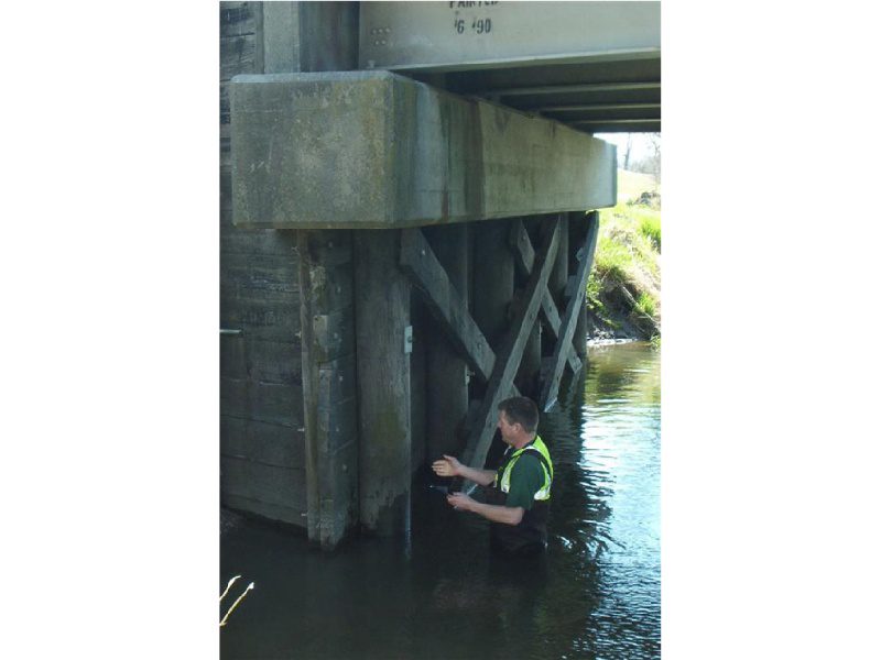 A man in the water under a bridge.