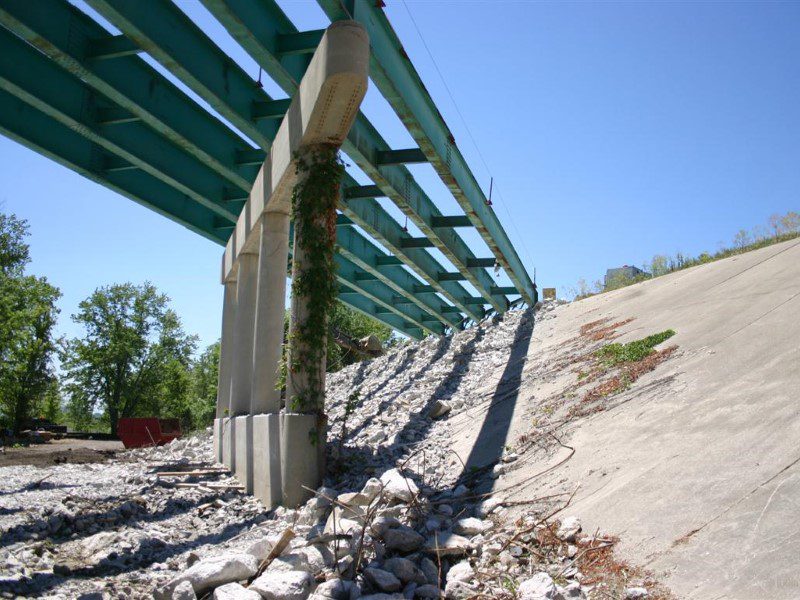 A view of the side of a bridge from below.